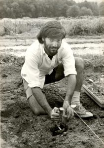 Student with a hand trowel digging in the dirt